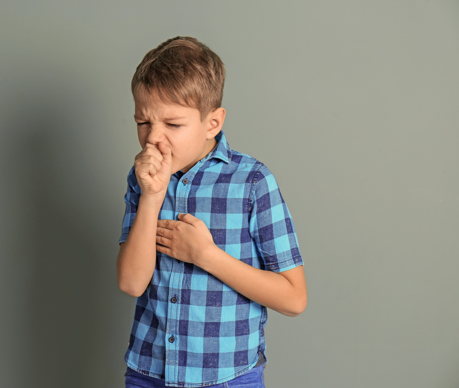 Male child in blue shirt coughing