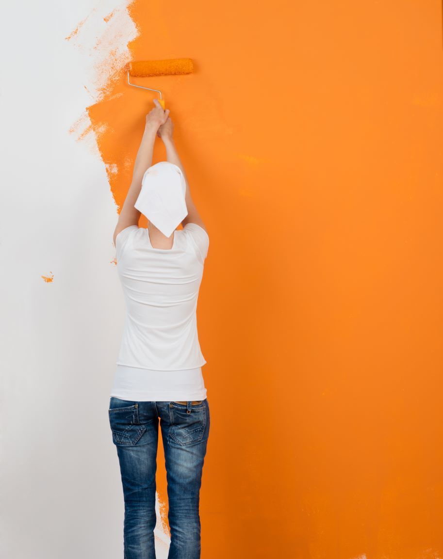 Woman painting wall orange with roller